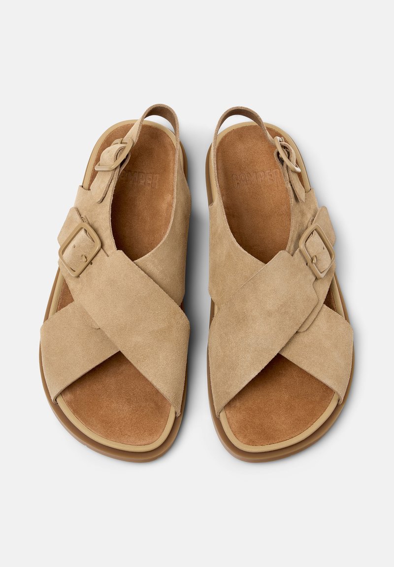 Sandalias de ante beige con correas anchas cruzadas, hebillas ajustables y plantillas acolchadas, vista desde arriba sobre un fondo blanco.