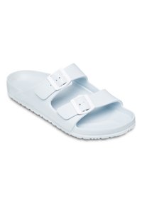 Ljusblåa halkskydd i slätt material, med två justerbara vita spännen, öppen tådesign och strukturerad sula för grepp.