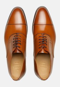 Braune Lederbrottschuhe mit polierter Oberfläche, runder Spitze, traditionellem Schnürdetail und glattem, nahtlosem Design.