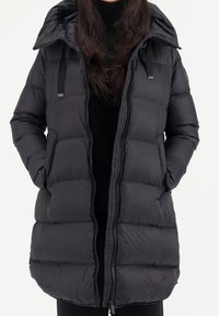 Zwarte pufferjack met capuchon, met doorgestikte secties, dubbele voorzakken, een volledige ritssluiting en zwarte accentbanden op de capuchon.