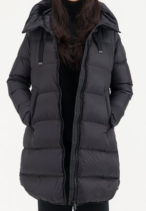 Svart puffjacka med huva, med kviltade sektioner, två framfickor, en hel dragkedja och svarta accentband på huvan.