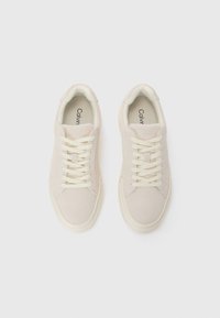Beige semskede sneakers med en glat tekstur, kremfargede snørelisser og rund tådesign. "Calvin Klein" logo er synlig på tungen.