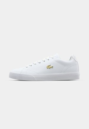 White leather sneakers with a smooth texture, round toe, flat laces, gold logo accent, and a textured rubber sole.