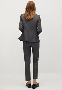 Szary blazer w wzory z dopasowanymi spodniami typu slim fit, wykonany z teksturowanej tkaniny. Buty są czarne z masywną podeszwą.