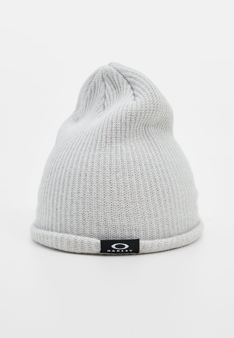 Gorro de punto gris con textura acanalada, con un puño doblado y una etiqueta de logo negra con un diseño circular en la parte frontal.