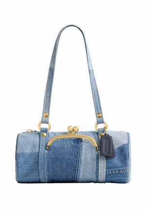 Petit sac à main cylindrique en patchwork de denim avec longues anses, fermoir doré et étiquette noire de la marque suspendue sur fond blanc.