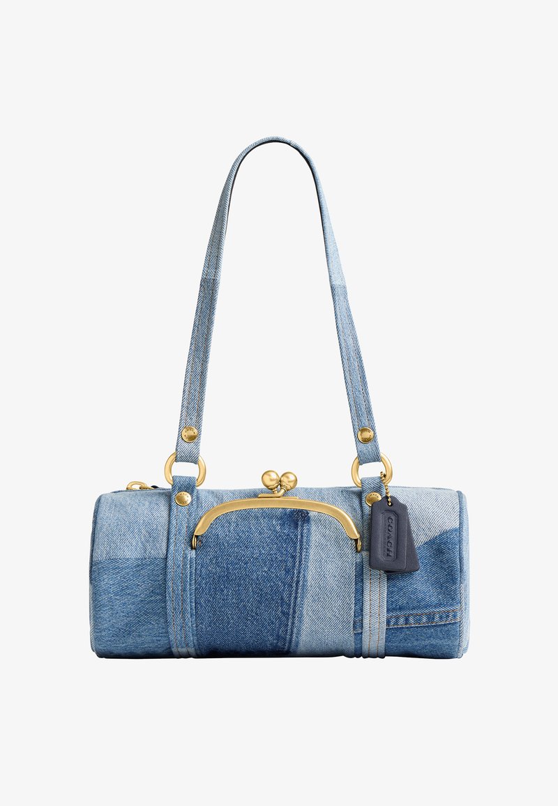 Petit sac à main cylindrique en patchwork de denim avec longues anses, fermoir doré et étiquette noire de la marque suspendue sur fond blanc.