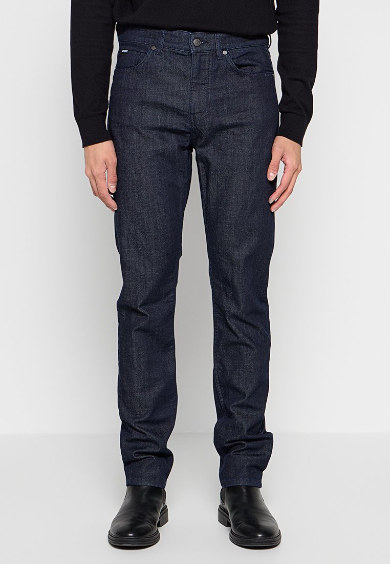 Dunkelblaue Jeans aus Denim mit schmaler Passform. Verfügt über fünf Taschen und einen Metallknopfverschluss. Glatte Textur, minimale Nähdetails.