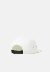 Hvit fempanel cap med justerbar svart rem, flat skjerm og ventilasjonsøyer, vist fra baksiden mot en hvit bakgrunn.
