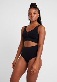 Svart sømløs sports-BH med brede stropper og myk tekstur, kombinert med høyt midje svart undertøy med en glatt overflate og minimalistisk design.