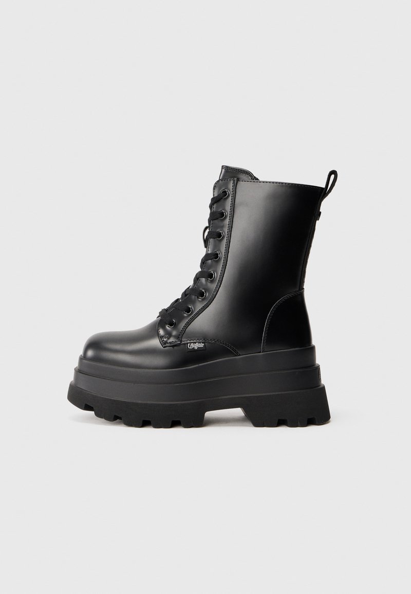 Botas de tobillo negras con cordones y suela de plataforma gruesa, acabado de cuero suave y tirador. Cuenta con ocho ojetes y suela texturizada.
