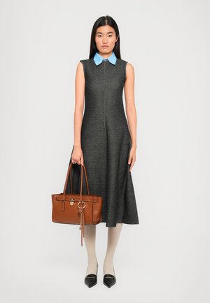 Abito grigio senza maniche con colletto azzurro, indossato con leggings beige e scarpe nere con punta. Una borsa marrone è tenuta nella mano destra.