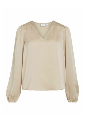 Beżowa bluzka z długim rękawem i dekoltem w serek, z marszczeniami na ramionach i gładką, jedwabistą teksturą. Prosty, luźny krój.