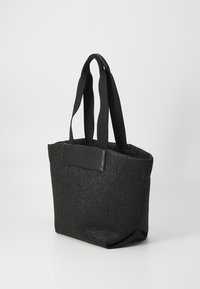 Czarna pleciona torba na ramię z szerokimi materiałowymi uchwytami i skórzanym wykończeniem, stojąca pod kątem na jasnym, jednolitym tle.