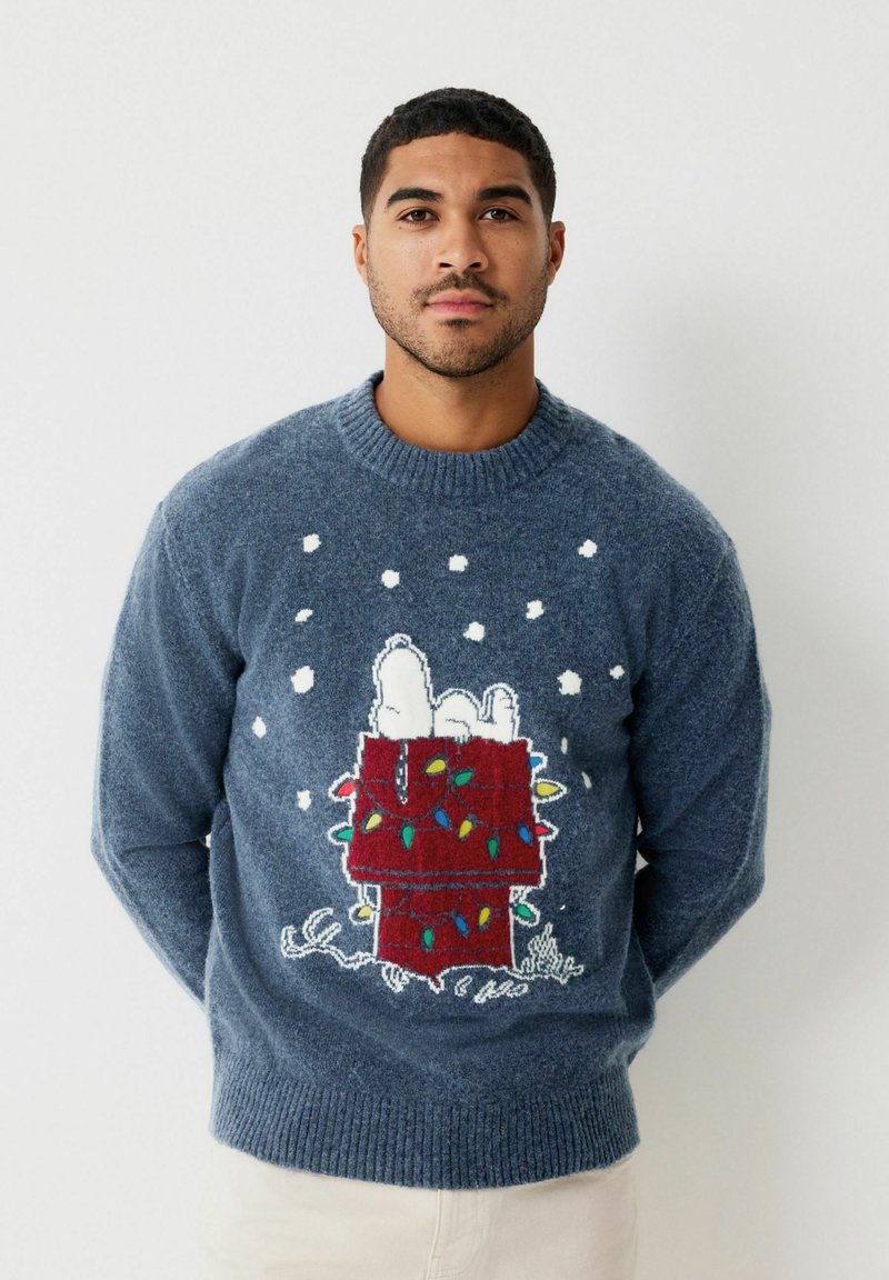 Maglione lavorato a maglia blu con design di Snoopy e una scatola regalo rossa. Decorato con luci decorative colorate e fiocchi di neve bianchi. Finitura texturizzata.