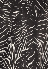 Motif abstrait noir et blanc en rayures de zèbre avec des lignes irrégulières et fluides sur une surface textile.