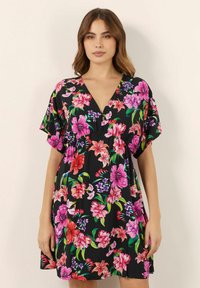 Abito nero floreale con maniche corte, scollatura a V e fiori vivaci rosa, rossi e viola, caratterizzato da un design morbido e fluido in un tessuto leggero.