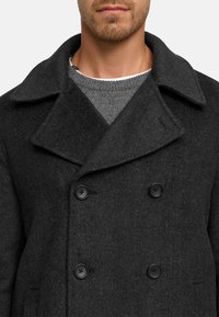 Abrigo peacoat de lana gris oscuro con un amplio cuello, que presenta botones negros y una textura suave. Superpuesto a un suéter de punto gris.