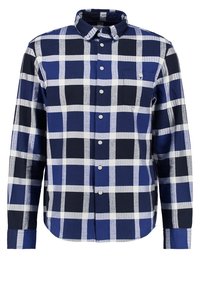 Chemise à manches longues à carreaux bleus, noirs et blancs avec une poche poitrine avant et un col boutonné.