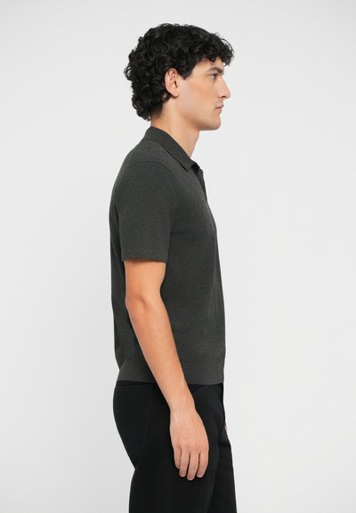Polo cu mânecă scurtă în gri închis, fabricat din material texturat. Prezintă o guler clasic și o croială ajustată, complementat cu o pereche de pantaloni negri.