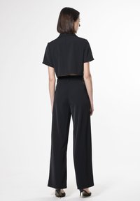 Zwart cropped shirt met korte mouwen, gecombineerd met hoge taille zwarte wijde broek, minimalistisch design, soepele textuur en geen zichtbare accenten.