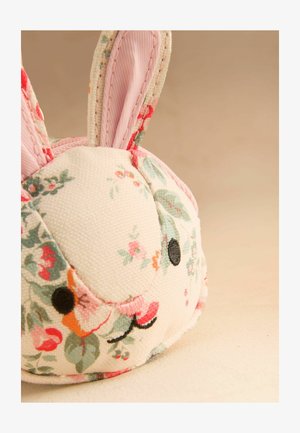 Täidetud kangast jänkupea tikanditega mustade silmade, roosa nina ja lillemustriga kreemilisel taustal beeži pinna taustal.