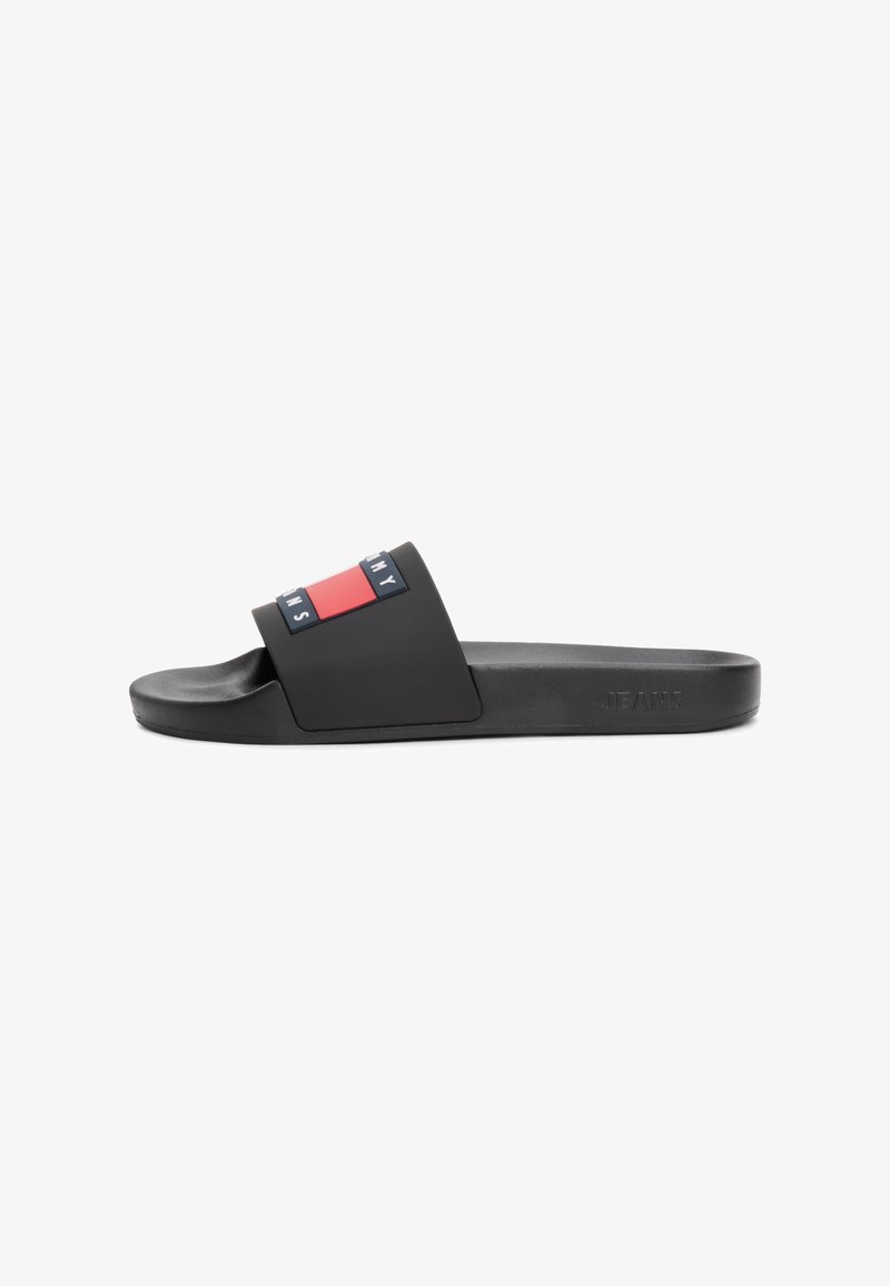 Sandale à enfiler noire avec une large sangle présentant un logo Tommy Jeans rouge, blanc et bleu sur le dessus.