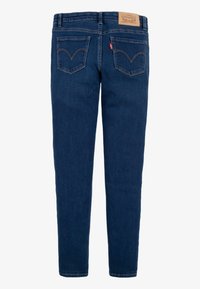 Tumesinised teksapüksid sirge säärega, viie taskuga, selgelt eristuva tagatasku õmblusega ning vöökohal nahast kaubamärgiga plaastriga.