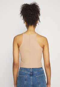 Top corto a coste nudo con spalline sottili, dotato di zip sul retro e design aderente. Abbinato a pantaloni corti in denim a vita alta.