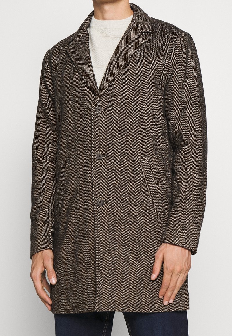 Brauner Herringbone-Mantel mit Reverskragen, drei Knöpfen und vorderen Taschen; strukturierter Stoff; taillierte Passform.