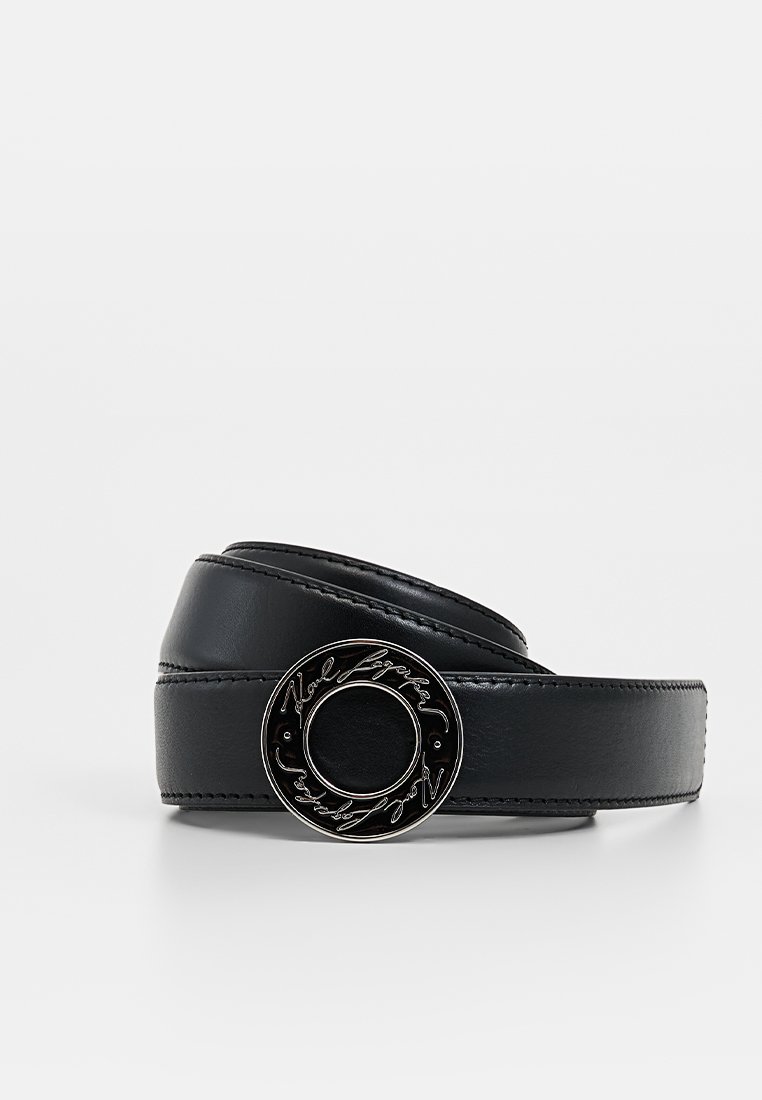 Ceinture en cuir noir avec une boucle ronde en métal argenté ornée d'une inscription décorative. Texture lisse et structure ferme, conçue pour une durabilité accrue.