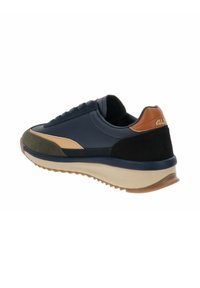 Zapatilla deportiva en azul marino y verde olivo con una suela beige, confeccionada en materiales de ante y cuero, con acentos texturizados contrastantes a lo largo del costado.