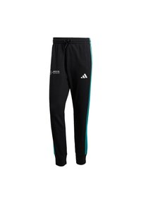 Black sweatpants made of soft fabric with turquoise side stripes, featuring an embroidered logo on the front and an elastic waistband.