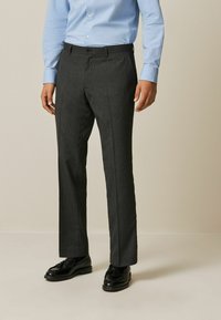 Men's dark gray tailored trousers with a subtle striped texture, featuring a button closure and front pockets, complemented by black dress shoes.