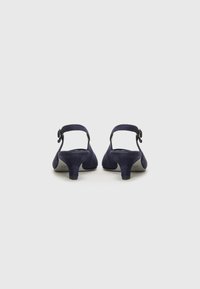 Sandales à talons en daim bleu marine avec une sangle autour de la cheville et une boucle circulaire, dotées d'un talon épais modéré.
