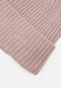 Gorro de malha rosa com textura canelada e aba dobrada. A parte da frente apresenta um logo "CK" bordado na mesma cor.