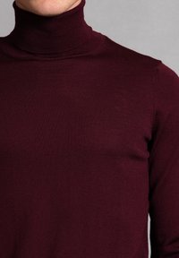 Burgundowa sweter z golfem wykonany z materiału ryżowego. Dopasowany krój z długimi rękawami i wysokim kołnierzem. Gładka tekstura.