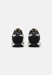 Baskets noires et vert olive en suède et mesh, avec une semelle intermédiaire blanche épaisse et une semelle extérieure en caoutchouc à traction texturée.