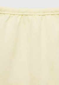Tessuto giallo chiaro con una superficie liscia. La vita presenta cuciture arricciate per maggiore flessibilità. Colore uniforme e semplice, senza motivi.