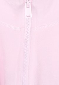 Capirote rosa soft con zip centrale bianca e cuciture piatte sulle cuciture, con una finitura liscia e strutturata.