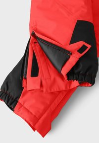 Röd jacka med svarta accenter som har dragkedja och kardborre-fickor, samt en justerbar manschettdesign för anpassad passform.