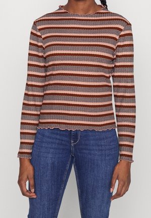 Gestreepte lange mouwen top in bruin, roze en crème met een scalloped halslijn en ribbeltextuur; gecombineerd met blauwe spijkerbroek.