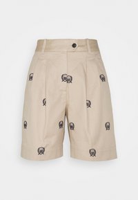 Beige šortky vyrobené z bavlny s záhyby, s tmavě modrými vyšívanými logy na náprsní kapse a zapínáním na knoflík v pase.