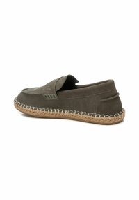 Zapato sin cordones de ante verde olivo con suela de yute cosida y un detalle decorativo de correas en la parte superior, con un acabado texturizado.