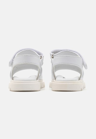 Sandali bianchi con apertura sul retro, fasce larghe e chiusure in velcro. Suola in gomma con grip strutturato. Design minimalista e finitura liscia.