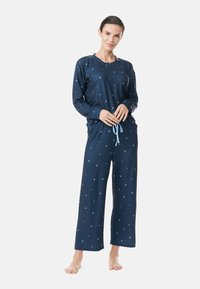 Marinblå pyjamasset med lång ärm och vida byxor. Har ett ljusblått stjärnmönster och dragsko i midjan. Mjuk, strukturerad tyg.