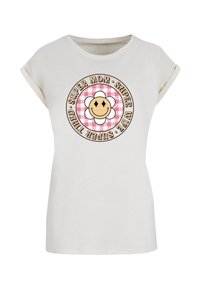 Short-sleeve, cream-colored t-shirt featuring a round graphic with a smiling flower on a pink checkered background and text.