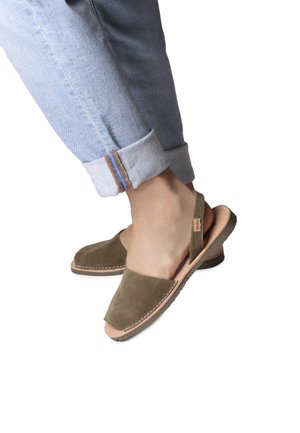 Olivgröna mocka slingback-sandaler med rund tå, beige lädersula och vit sömnad. Matchas med uppvikta ljusblå jeans.