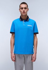 Blå polo skjorta i bomull med klassisk krage. Den har en marinblå och vit randig krage och en logotyp på bröstet.