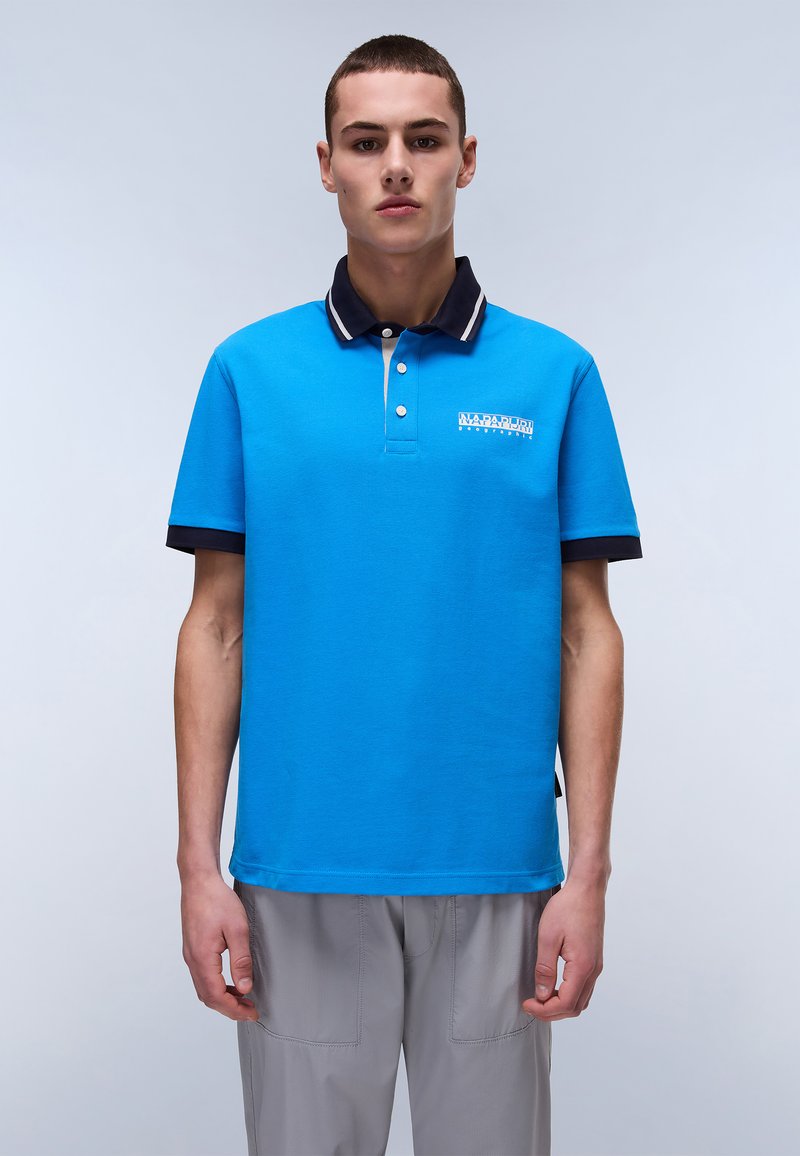 Blå polo skjorta i bomull med klassisk krage. Den har en marinblå och vit randig krage och en logotyp på bröstet.